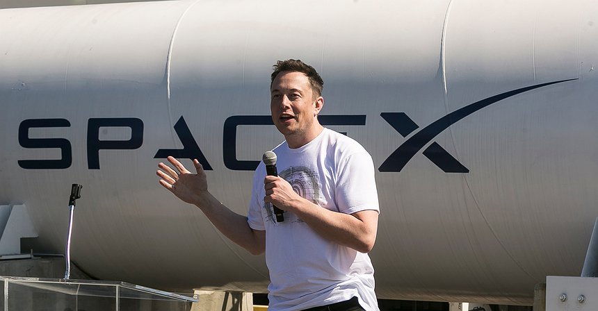 Elon Musk speaking in front of a SpaceX rocket